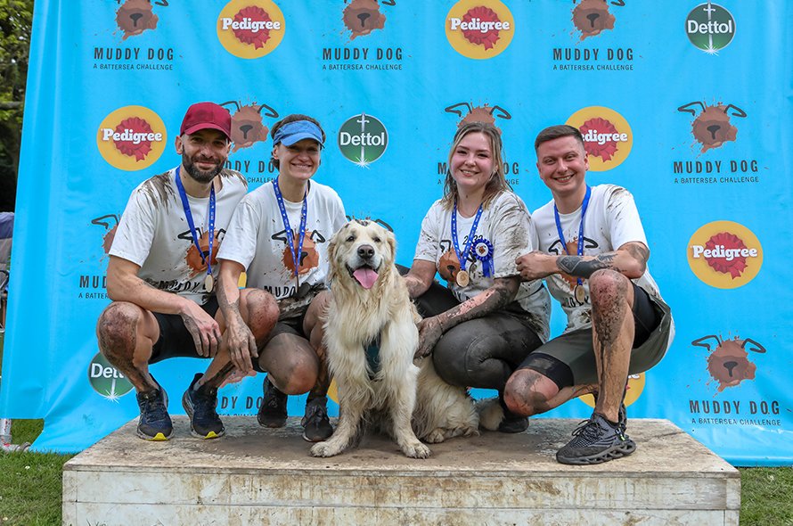 Four people with their dog after the muddy dog event