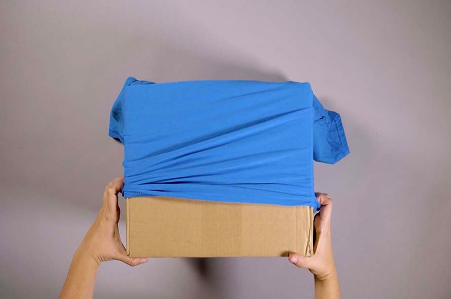 A t-shirt being stretched over a cardboard box 