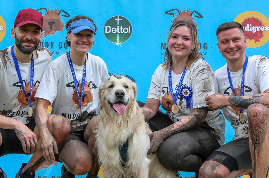 People posing in front of a sign with a dog