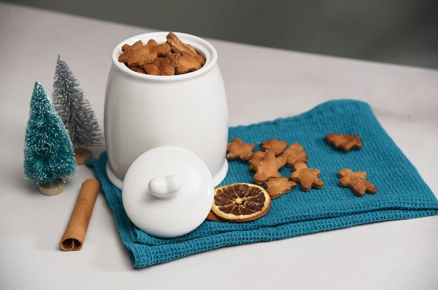 Jar of Christmas dog treats on tea towel with festive decorations