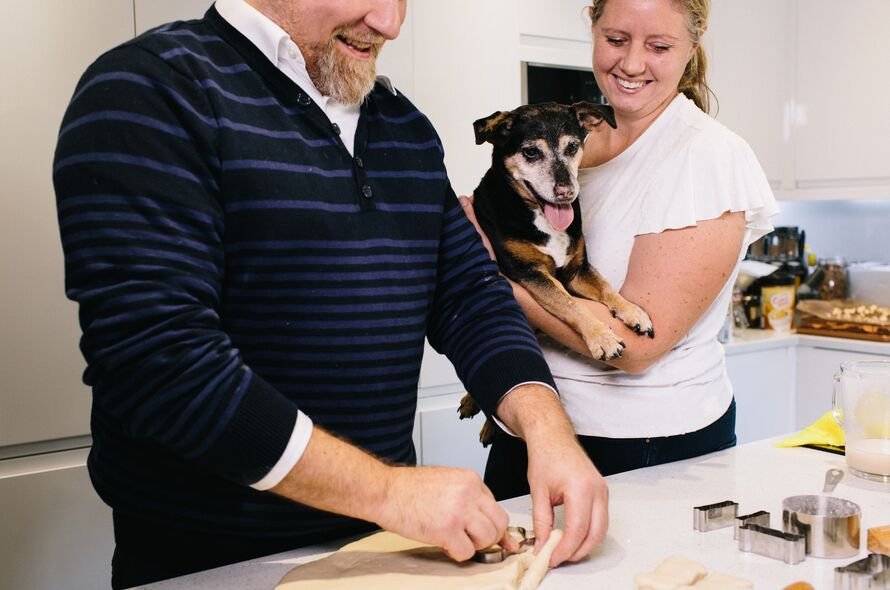 Two happy owners making biscuits in their kitchen