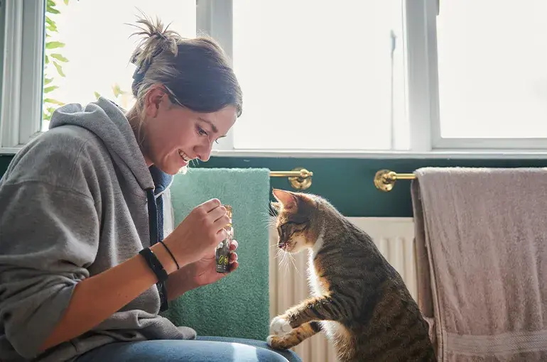Woman and her cat looking at a bottle 