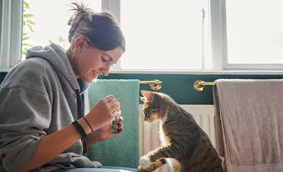 Woman and her cat looking at a bottle 